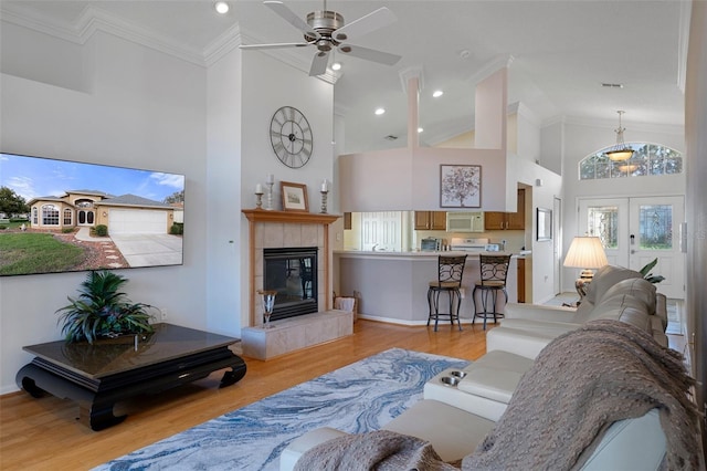 living area featuring high vaulted ceiling, a ceiling fan, crown molding, and light wood finished floors