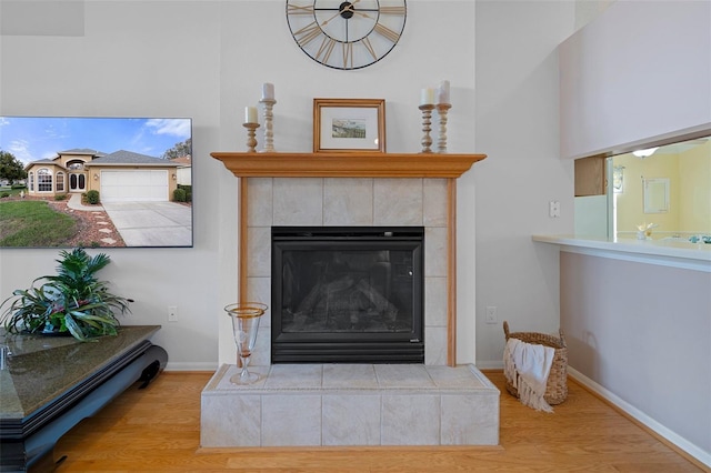 details featuring baseboards, wood finished floors, and a tiled fireplace