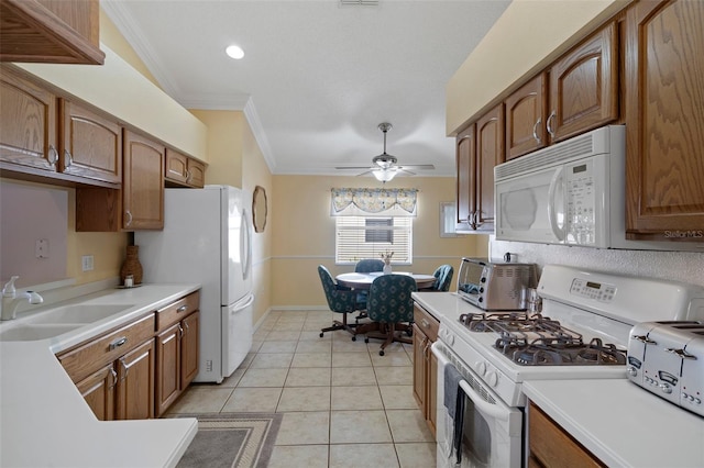 kitchen with light countertops, crown molding, white appliances, a sink, and light tile patterned floors