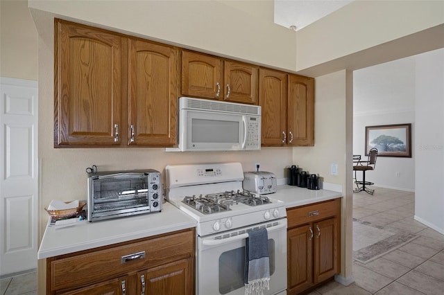 kitchen with light countertops, a toaster, white appliances, brown cabinetry, and light tile patterned floors