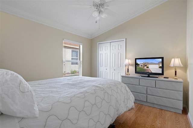 bedroom featuring a closet, crown molding, light wood finished floors, a ceiling fan, and lofted ceiling