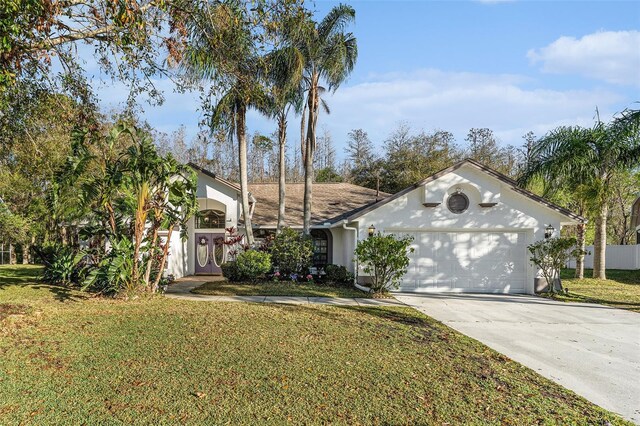 view of front of home featuring a garage, concrete driveway, a front yard, and stucco siding