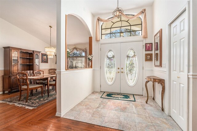 foyer featuring a chandelier, high vaulted ceiling, french doors, and baseboards