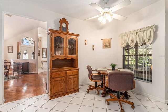 dining room featuring a ceiling fan, light tile patterned flooring, vaulted ceiling, and baseboards