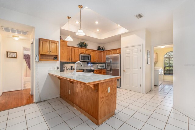 kitchen with stainless steel appliances, brown cabinets, visible vents, and a peninsula