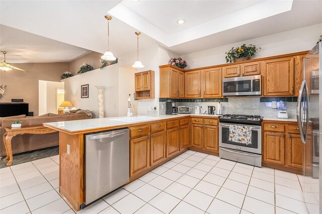 kitchen featuring open floor plan, decorative light fixtures, a peninsula, stainless steel appliances, and light countertops