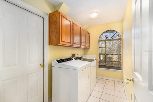 clothes washing area featuring cabinet space, washing machine and dryer, light tile patterned floors, and baseboards