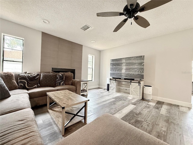 living area with light wood-style floors, visible vents, plenty of natural light, and baseboards