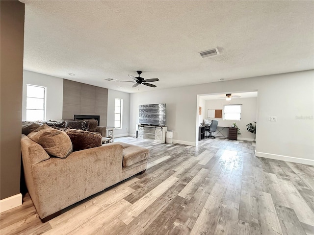 living area featuring plenty of natural light, light wood-style flooring, visible vents, and a textured ceiling