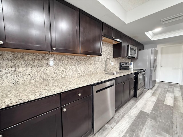 kitchen with a raised ceiling, visible vents, appliances with stainless steel finishes, a sink, and dark brown cabinets