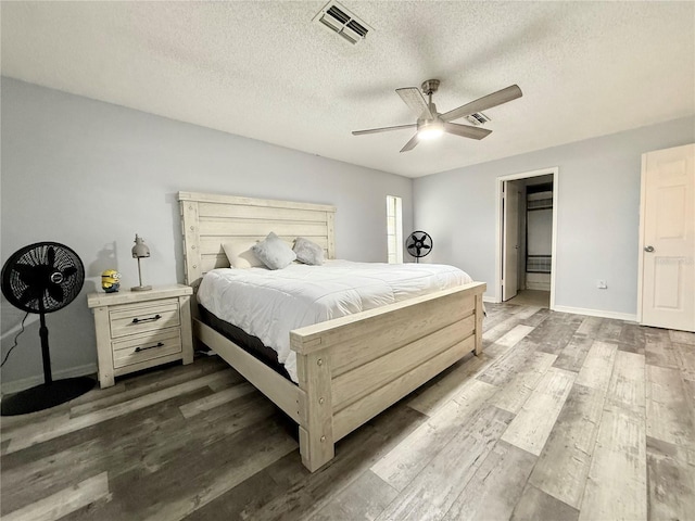 bedroom with baseboards, visible vents, dark wood finished floors, and a textured ceiling