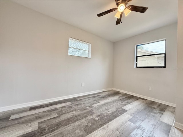 spare room featuring a healthy amount of sunlight, ceiling fan, baseboards, and wood finished floors