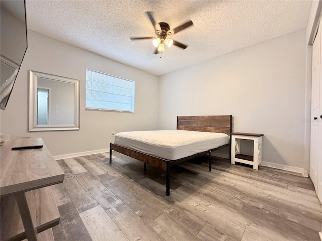 bedroom featuring a textured ceiling, wood finished floors, a ceiling fan, and baseboards