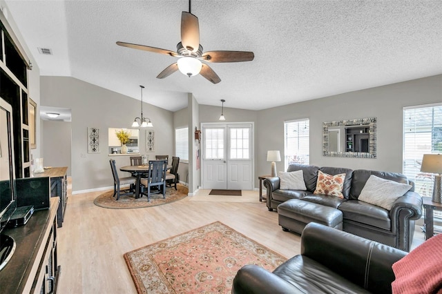 living room featuring lofted ceiling, ceiling fan with notable chandelier, a wealth of natural light, and hardwood / wood-style floors