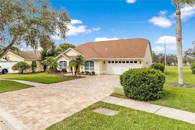 view of front facade featuring an attached garage, stucco siding, decorative driveway, and a front yard