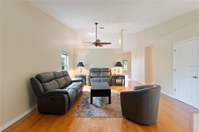 living room with light wood-style floors, baseboards, vaulted ceiling, and a ceiling fan