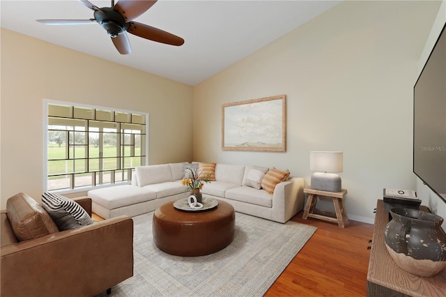 living area with a ceiling fan, lofted ceiling, baseboards, and wood finished floors