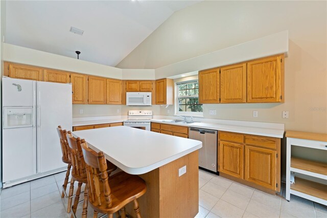 kitchen featuring white appliances, light countertops, a sink, and a center island