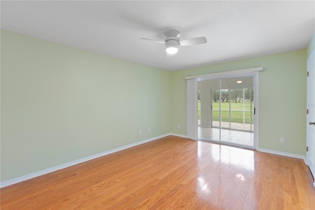 unfurnished room with ceiling fan, light wood finished floors, a textured ceiling, and baseboards