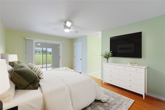 bedroom with access to outside, wood finished floors, a ceiling fan, and baseboards