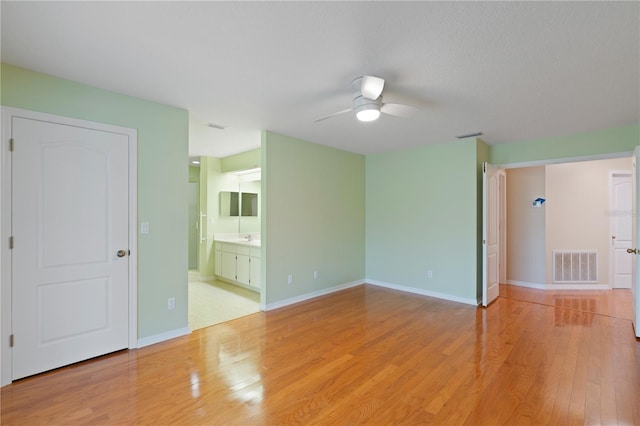 empty room featuring baseboards, light wood-style flooring, visible vents, and a ceiling fan