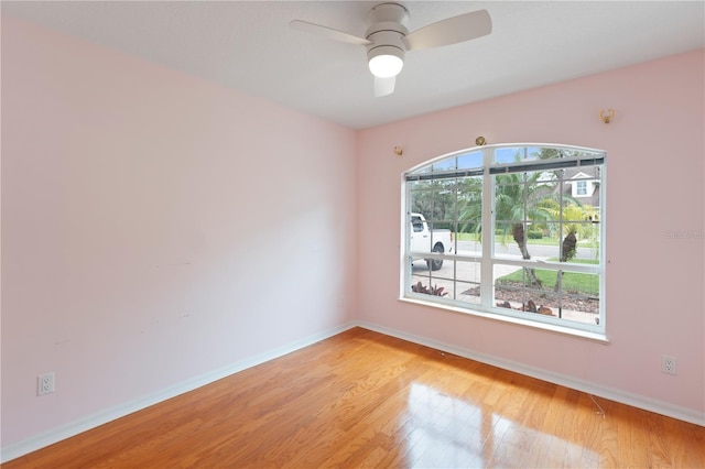 spare room with ceiling fan, light wood finished floors, and baseboards