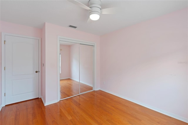 unfurnished bedroom featuring light wood finished floors, baseboards, visible vents, ceiling fan, and a closet