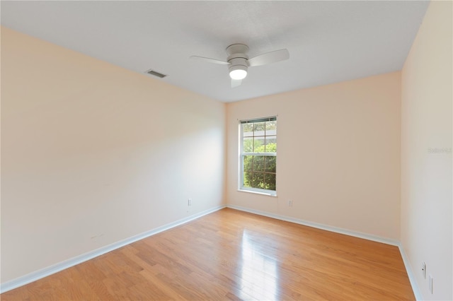 spare room with light wood finished floors, baseboards, visible vents, and a ceiling fan