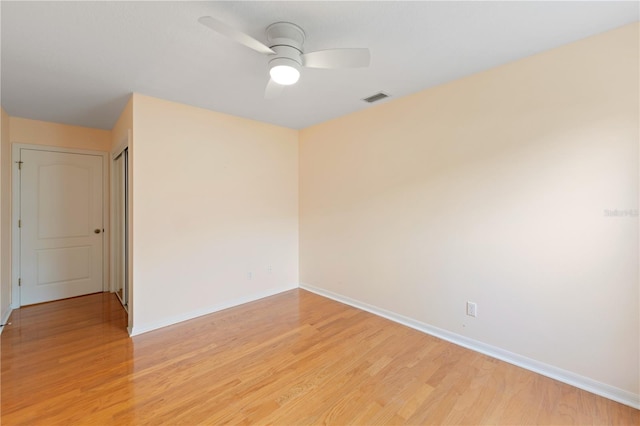 unfurnished room with a ceiling fan, light wood-type flooring, visible vents, and baseboards