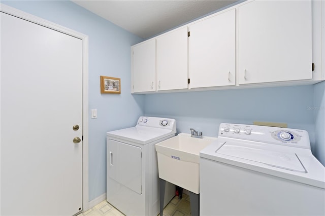 washroom featuring a sink, washing machine and clothes dryer, and cabinet space