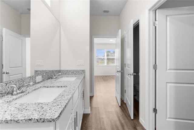 bathroom with double vanity, visible vents, a sink, and wood finished floors