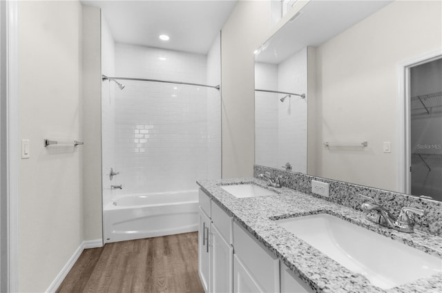 full bathroom featuring double vanity, a spacious closet, wood finished floors, and a sink