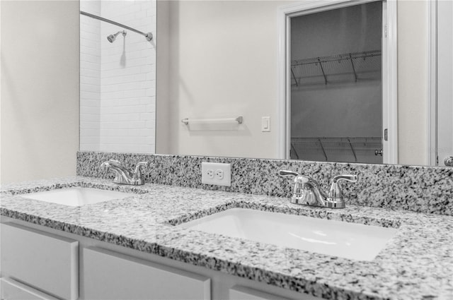 bathroom featuring a walk in closet, a sink, and double vanity