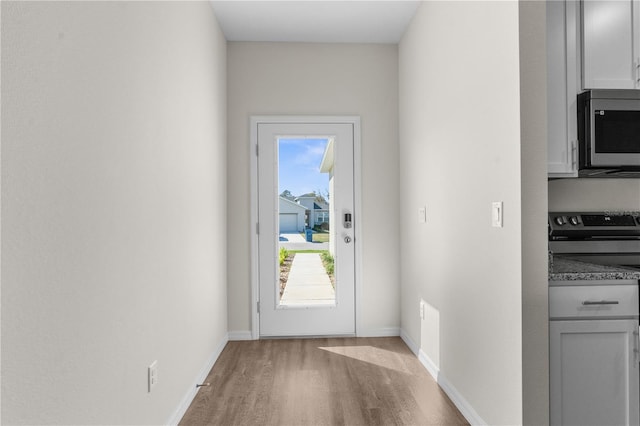 doorway featuring baseboards and wood finished floors