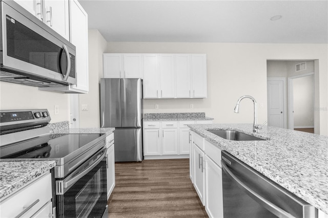 kitchen with stainless steel appliances, white cabinets, a sink, and light stone counters