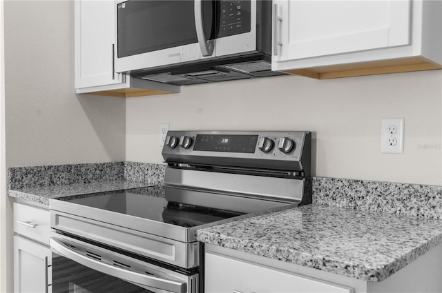 kitchen featuring appliances with stainless steel finishes, white cabinets, and light stone countertops