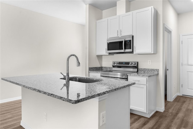 kitchen with appliances with stainless steel finishes, a sink, a center island with sink, and white cabinets