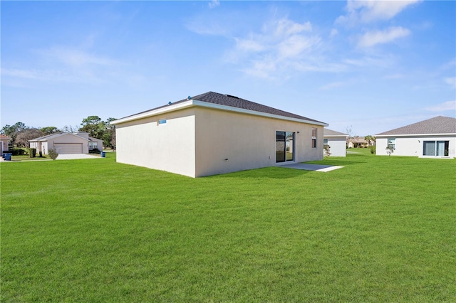 back of house featuring stucco siding and a yard