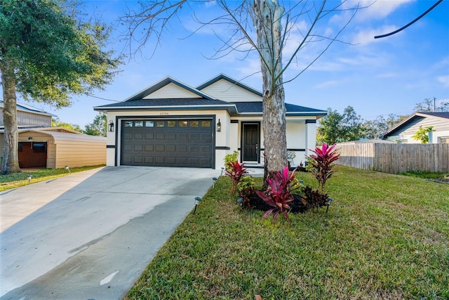 view of front facade featuring a garage, concrete driveway, fence, a front yard, and stucco siding