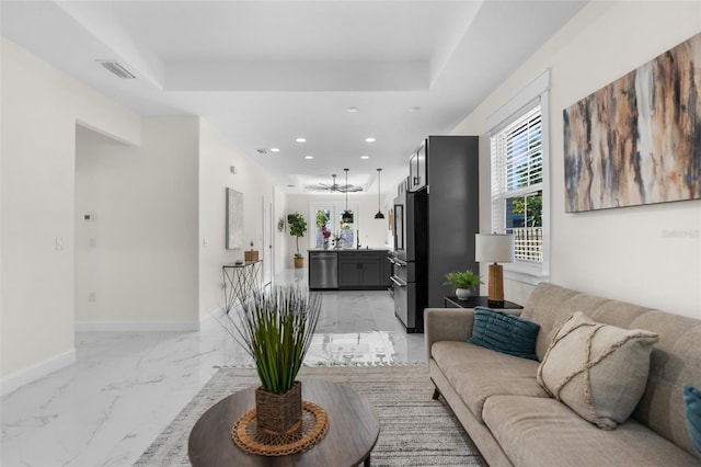 living room with baseboards, visible vents, marble finish floor, a tray ceiling, and recessed lighting