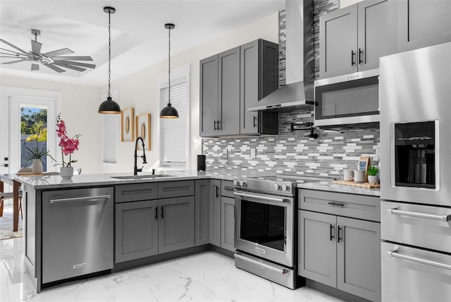 kitchen featuring stainless steel appliances, gray cabinetry, a peninsula, and wall chimney exhaust hood