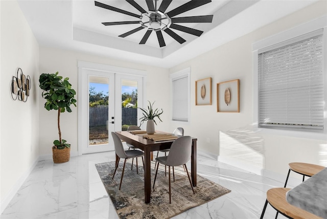 dining space with ceiling fan, baseboards, marble finish floor, french doors, and a tray ceiling