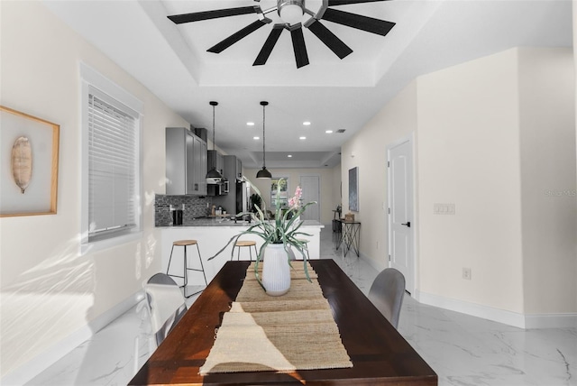 dining space featuring baseboards, a ceiling fan, marble finish floor, a tray ceiling, and recessed lighting