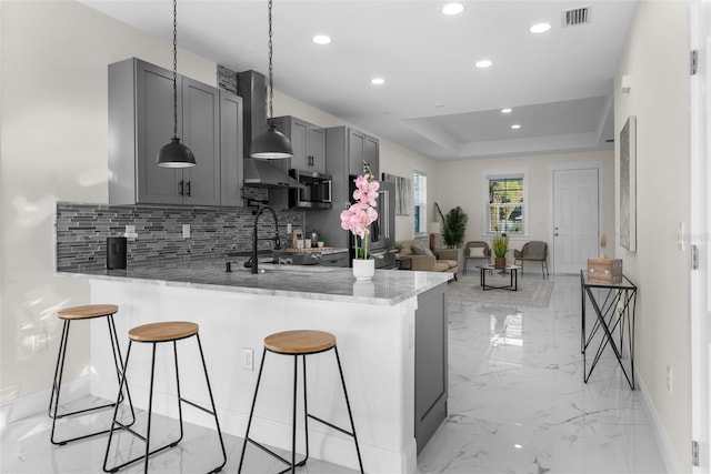 kitchen featuring a peninsula, stainless steel appliances, visible vents, gray cabinets, and a tray ceiling