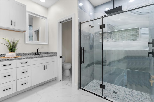 bathroom featuring toilet, marble finish floor, a shower stall, and vanity