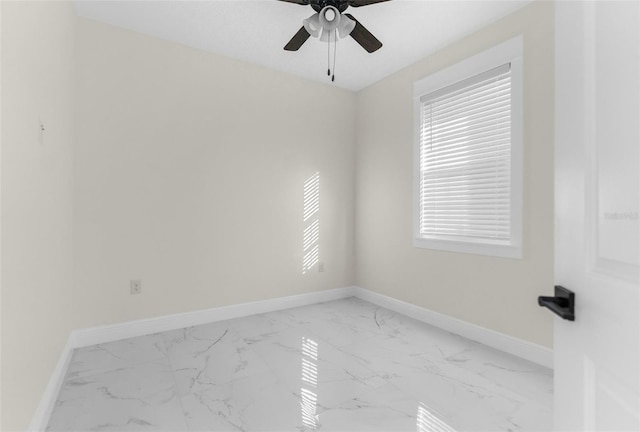 empty room featuring ceiling fan, marble finish floor, and baseboards