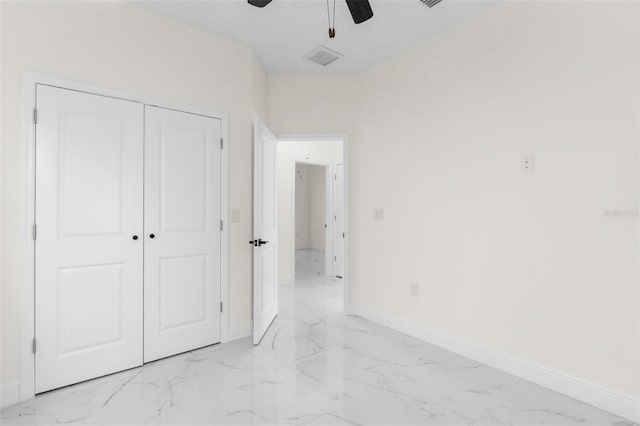 unfurnished bedroom featuring marble finish floor, a ceiling fan, baseboards, and a closet