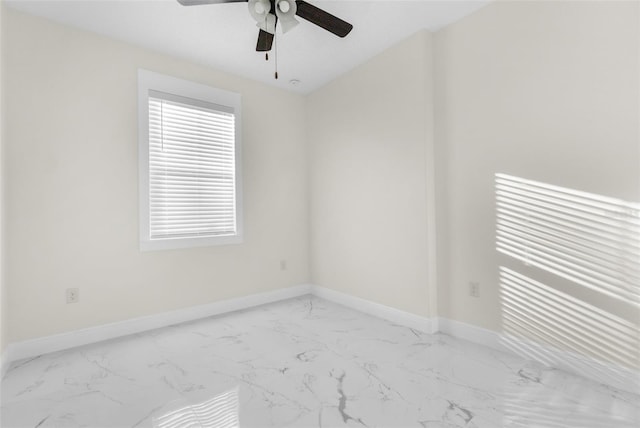 spare room with marble finish floor, ceiling fan, and baseboards