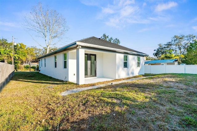 rear view of property featuring a patio area, a fenced backyard, a lawn, and stucco siding