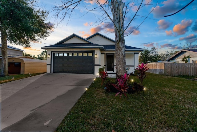 view of front of house with a garage, fence, concrete driveway, stucco siding, and a front yard